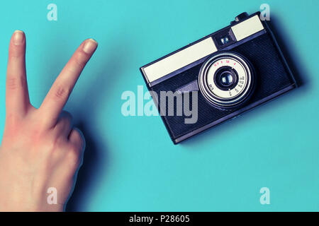 Alte Kamera auf einem blauen Hintergrund neben Geste Sieg hand Stockfoto