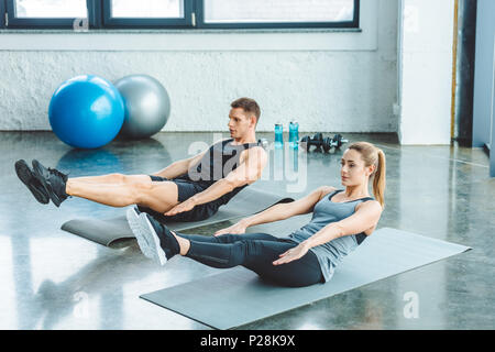 Paar tun abs-Übungen auf Matten vor dem Training im Fitnessraum Stockfoto