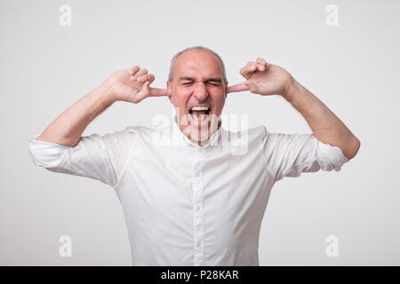 Reifen europäischen Mann seine Ohren schließen wegen der lauten Klang und Geräusch. Ich will nicht auf sie hören. Stockfoto