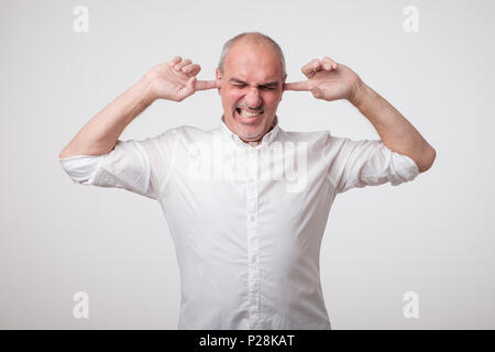 Reifen europäischen Mann seine Ohren schließen wegen der lauten Klang und Geräusch. Ich will nicht auf sie hören. Stockfoto