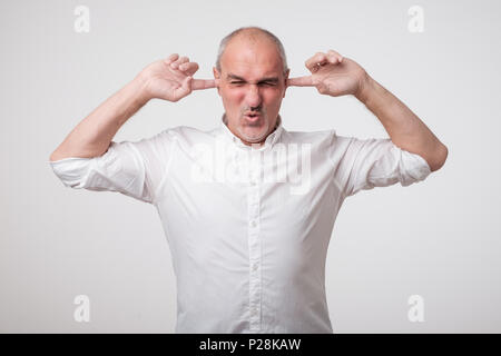 Reifen europäischen Mann seine Ohren schließen wegen der lauten Klang und Geräusch. Ich will nicht auf sie hören. Stockfoto