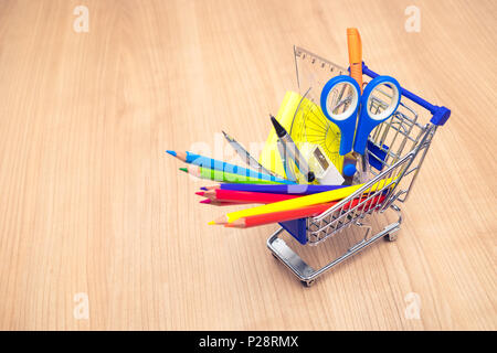 Shopping Cart mit Schulmaterial auf Tisch. Zurück zum Konzept der Schule Stockfoto