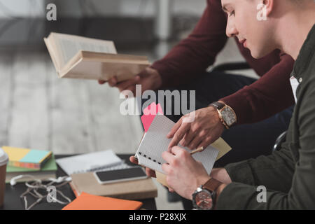 Zugeschnittenes Bild des Menschen verweist auf etwas in Freunde Notebook in der Bibliothek Stockfoto