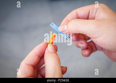 Patientin mit Schwangerschaft Diabetes halten in ihren Händen ein Orange glucometer Nadel mit Blut strip Test. Schwangerschaft diabetes Konzept Stockfoto