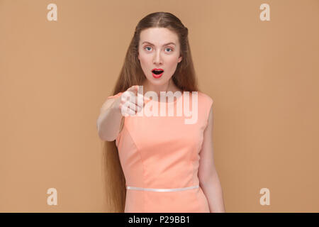 Wow, bist du das? Portrait von emotionalen Cute, schöne Frau mit Make-up und langes Haar in rosa Kleid. Indoor, studio Shot, isoliert auf Hellbraun oder Stockfoto