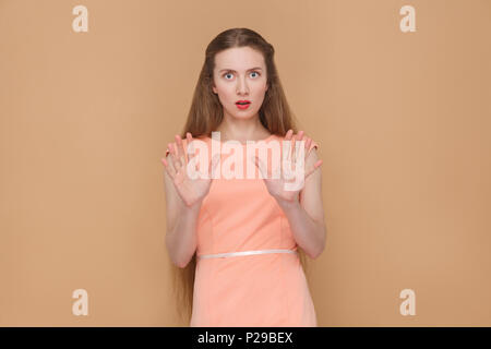 Angesichts der Panik Frau schockiert, an der Kamera schaut. Portrait von emotionalen Cute, schöne Frau mit Make-up und langes Haar in rosa Kleid. Indoor, Studio sh Stockfoto