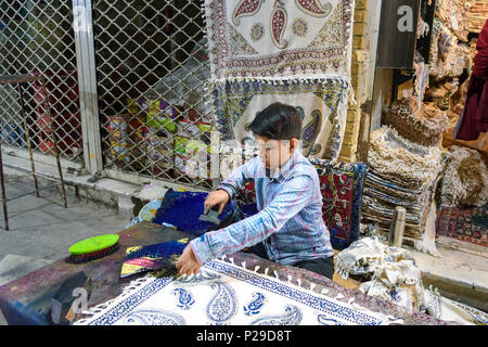 Isfahan, Iran - 21. März 2018: Iranische Junge mit geschnitzten hölzernen Block traditionelle Motive auf Textilien in Grand Bazaar zu Stempeln Stockfoto