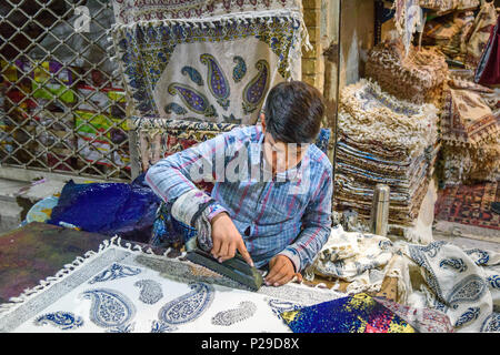 Isfahan, Iran - 21. März 2018: Iranische Junge mit geschnitzten hölzernen Block traditionelle Motive auf Textilien in Grand Bazaar zu Stempeln Stockfoto