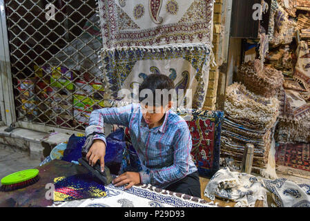 Isfahan, Iran - 21. März 2018: Iranische Junge mit geschnitzten hölzernen Block traditionelle Motive auf Textilien in Grand Bazaar zu Stempeln Stockfoto