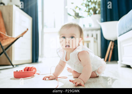 Cute Baby auf dem Boden sitzend zu Hause spielen mit Kopfhörer Stockfoto