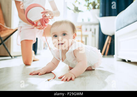 Cute Baby auf dem Boden sitzend zu Hause spielen mit Kopfhörer Stockfoto