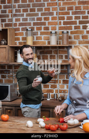 Mann schlägt Frau Gewürze in der Küche Stockfoto