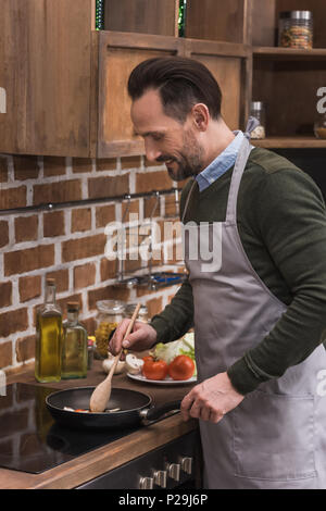 Schöner Mann rühren Gemüse Pfanne Stockfoto