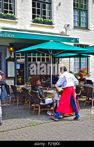 Eine hübsche farbige Frau Chats an den Kellner in einem Popluar City Centre Restaurant zu Mittag in Brügge oder Brügge, Belgien Stockfoto