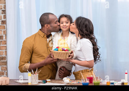 Afrikanische amerikanische Eltern küssen Tochter und Holding Stroh Korb mit Ostereiern Stockfoto