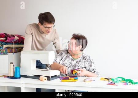 Small Business, Design, manufactoring Konzept. Von den alten lachen Frau gibt es einen Mann, er im leichten Pullover und Brillen gekleidet ist, ist der Mensch watchin Stockfoto