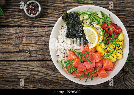 Hawaiian Lachs Fisch poke Schüssel mit Reis, Mango, Avocado, Tomate, Sesamsamen und Algen. Buddha Schüssel. Diät essen. Ansicht von oben. Flach Stockfoto