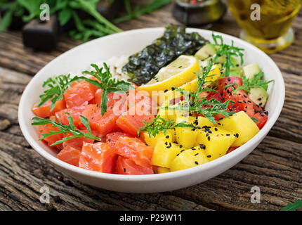 Hawaiian Lachs Fisch poke Schüssel mit Reis, Mango, Avocado, Tomate, Sesamsamen und Algen. Buddha Schüssel. Diät essen. Stockfoto