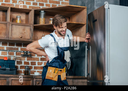 Handwerker leiden unter Rückenschmerzen während Festsetzung Kühlschrank Stockfoto