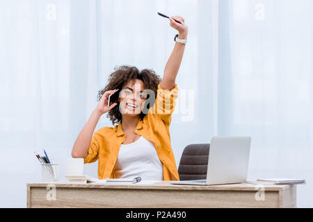 Schöne junge Frau im Gespräch per Telefon und heben die Hand glücklich Stockfoto