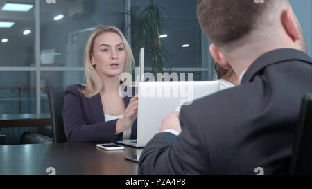 Blonde junge Geschäftsfrau, die die Arbeit mit Kollegen an der Konferenz im Büro kommunizieren. Stockfoto