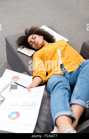Überarbeitete junge Frau schlafen auf der Couch nach der Arbeit zu Hause. Stockfoto