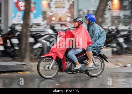 SAIGON, VIETNAM, 14.12.2017, Menschen mit einem regenmantel Fahrt auf dem Motorrad im Regen. Transport in der Stadt, wenn es regnet. Stockfoto