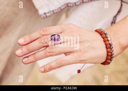 Weibliche hand mit Amethyst Stein ring und rudraksha Armband Stockfoto