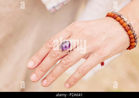 Weibliche hand mit Amethyst Stein ring und rudraksha Armband Stockfoto