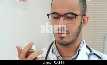 Männlicher Arzt texting auf einem Smartphone Stockfoto
