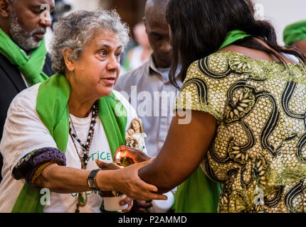 Eine ältere Frau wird ihr geholfen, Kerze eine verlorene Familie Mitglied im Dienst der Grenfell Feuer Jubiläum zu erinnern, in St. Helen's Church, South Kensington, London, England, UK, 14. Juni, 2018 Stockfoto