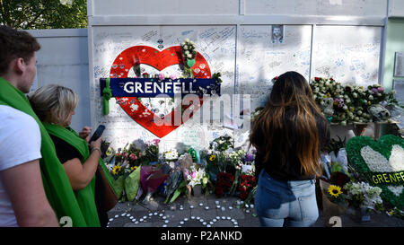 London, Großbritannien. 14. Juni 2018. Die Mauer der Erinnerung an der Basis der Grenfell Tower. Tribute gibt es in der Umgebung die 72 Leute, die auf dem Jahrestag der Tragödie Grenfell Turm, wo eine kleine Küche Feuer in die größte Blaze in Großbritannien gesehen seit dem Zweiten Welt Krieg getötet wurden, zu erinnern. Viele Menschen tragen grüne Schals - Grün für Grenfell - in Erinnerung an diese verloren. Credit: Stephen Chung/Alamy leben Nachrichten Stockfoto