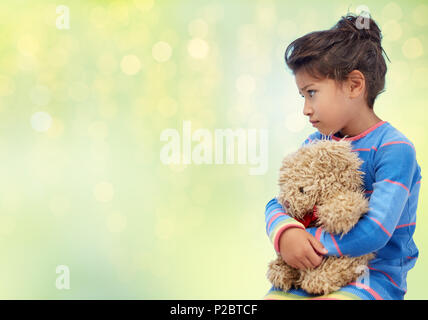 Trauriges kleines Mädchen mit Teddybär über Grüne Leds Stockfoto