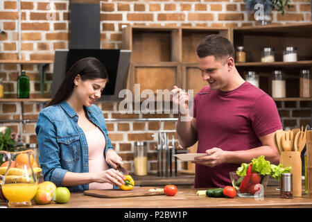 Glückliche junge Menschen und schwangere Frauen das gemeinsame Kochen in der Küche Stockfoto