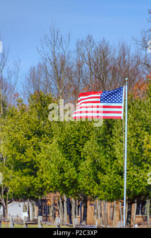 Die amerikanische Flagge, Sterne und Streifen, die im Wind flattern auf einem kühlen April Morgen, im Norden von Michigan. Star Spangled Banner. Rot, Weiß und Blau. Stockfoto