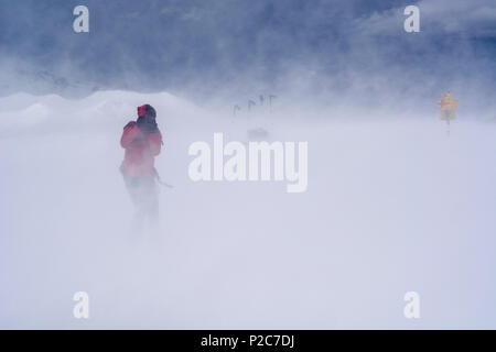 Ein backcountry Skier mit einer DSLR-Kamera, die ein Bild in einem Sturm durch Föhn Wind, Gipfel des Mattjisch Horn, hohe Val verursacht Stockfoto