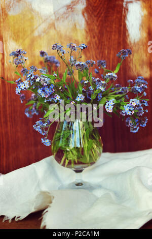 Blumenstrauß aus der frischen forget me nots auf dem weißen Serviette vor dem Hintergrund der polnischen Holz- Oberfläche Stockfoto