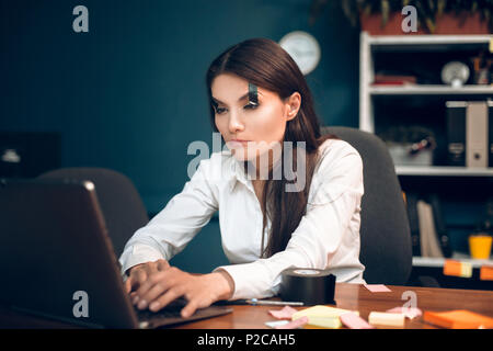 Frau, die versucht, ihre Augen offen zu halten, während Sie arbeiten. Stockfoto