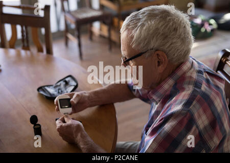 Älterer Mann seinen Blutzucker Kontrolle mit glucometer Stockfoto