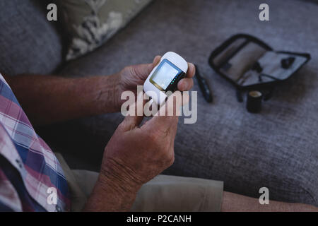 Älterer Mann seinen Blutzucker Kontrolle mit glucometer Stockfoto