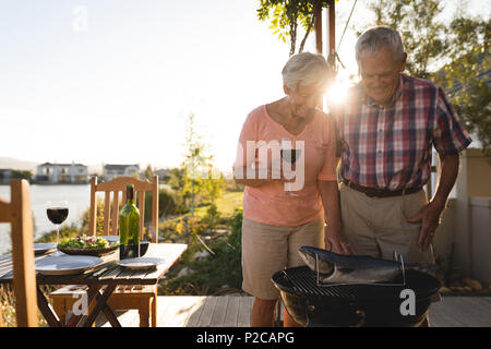 Senior paar Kochen Fisch auf dem Grill Stockfoto