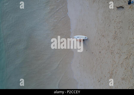 Frau mit Surfbrett am Strand zu sitzen Stockfoto