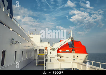 Susspended orange Rettungsboot an der Seite der Überfahrt mit der Fähre Deck auf das offene Meer Stockfoto
