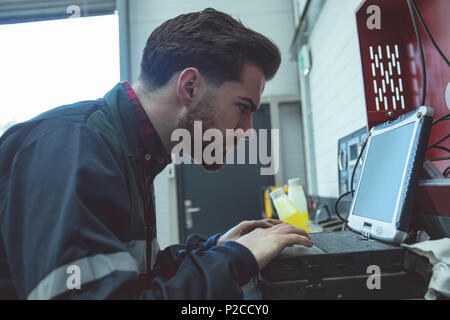 Aufmerksame Mechaniker mit Laptop Stockfoto