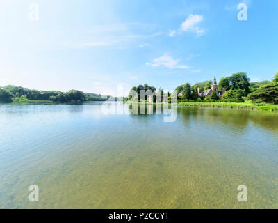 Newstead, England - 10. Juni 2018: Newstead Abbey See und das Fort. Die welligen Wasser des Sees spiegelt die Wolken und Bäumen gesäumten Seeufer. Stockfoto