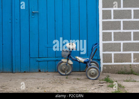 Ist kaputt Kinder Fahrrad auf dem Hintergrund der Garage Stockfoto