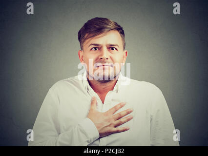 Junger Mann die Hand auf die Brust und entschuldigte sich mit Ausdruck von Reue und Schuld auf dem Gesicht Stockfoto