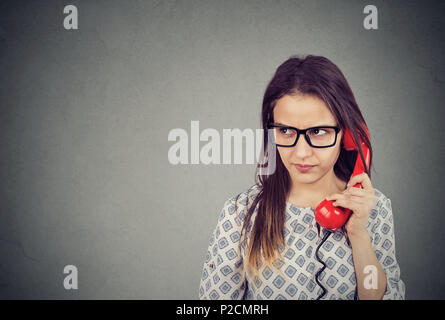 Junge Frau in Brillen sprechen auf altmodische Telefon weg im Unverständnis und Ärger suchen Stockfoto