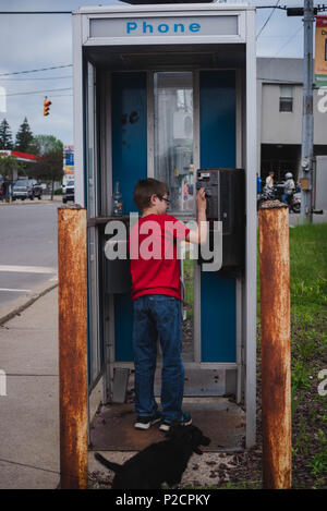 Ein Junge steht in einem alten Telefonzelle, die nicht mehr in den Vereinigten Staaten funktioniert. Stockfoto