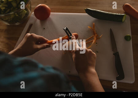Mädchen stehen in der Küche Schälen von Karotten mit dem Sparschäler zu Hause Stockfoto